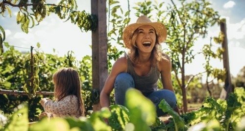 Young lady and her daughter laughing in their garden